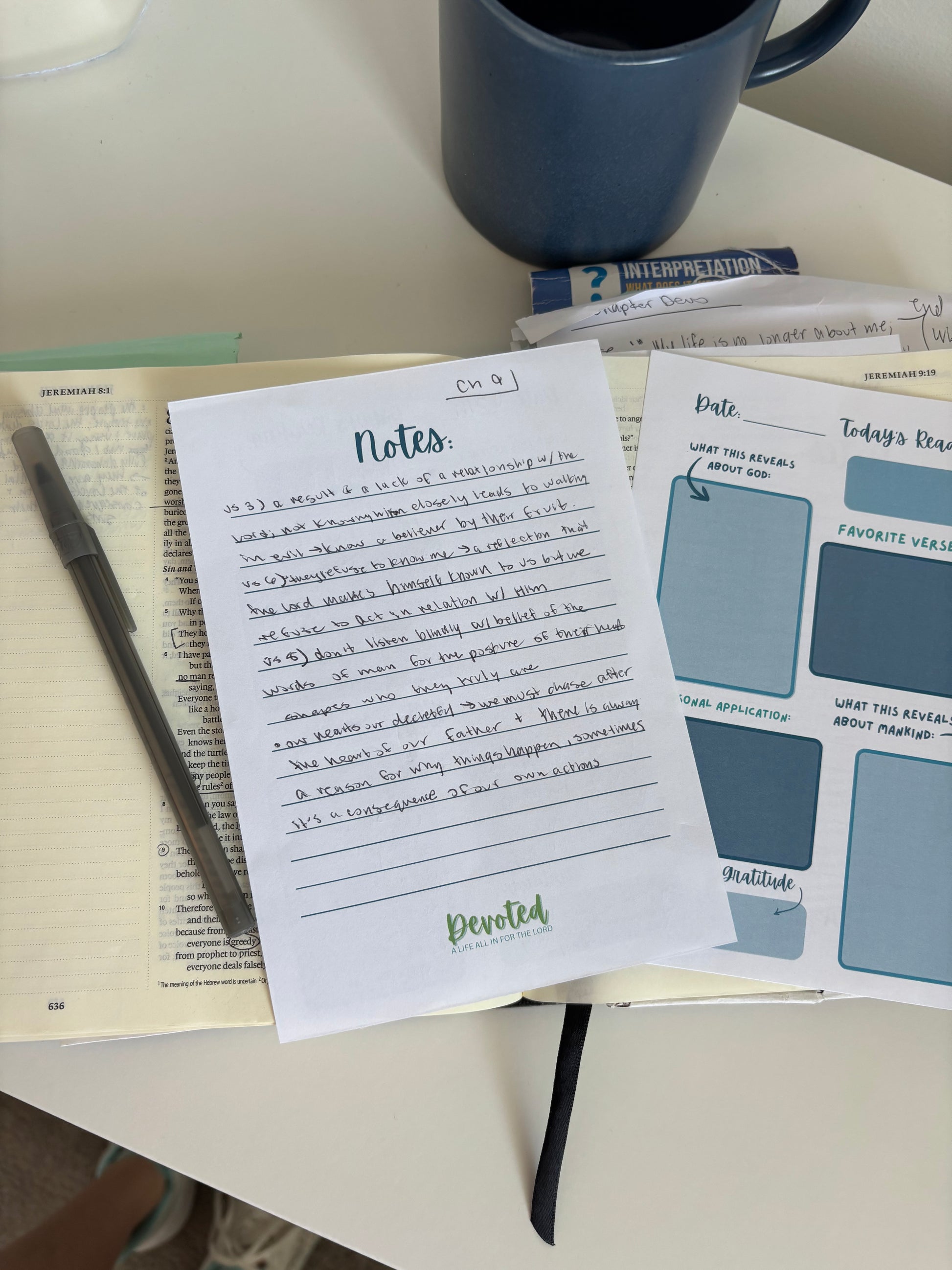 Notebook with printed pages, pen, and mug on a table