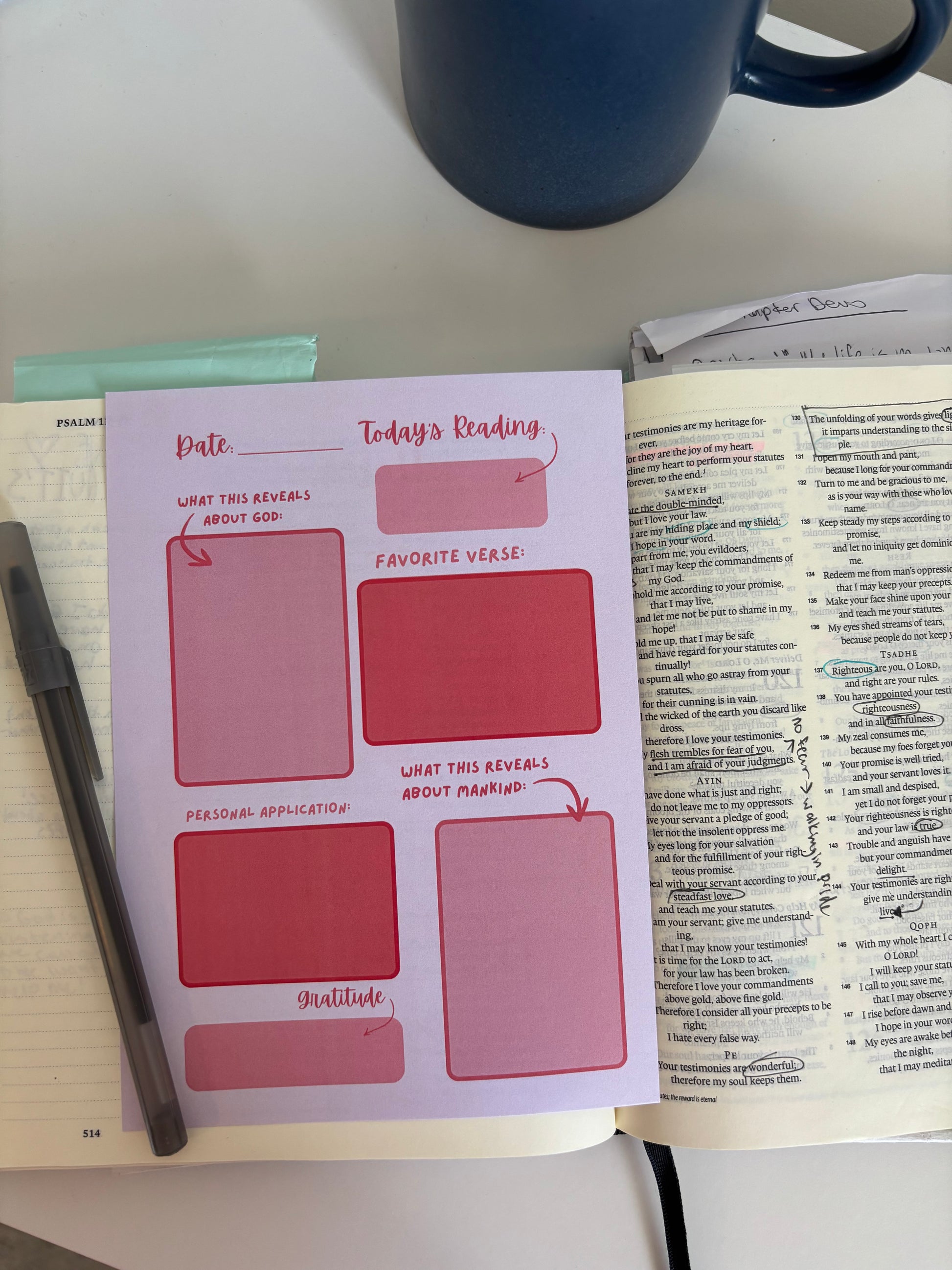 Notebook with reading planner stickers on top of an open book, with a pen and mug in the background.