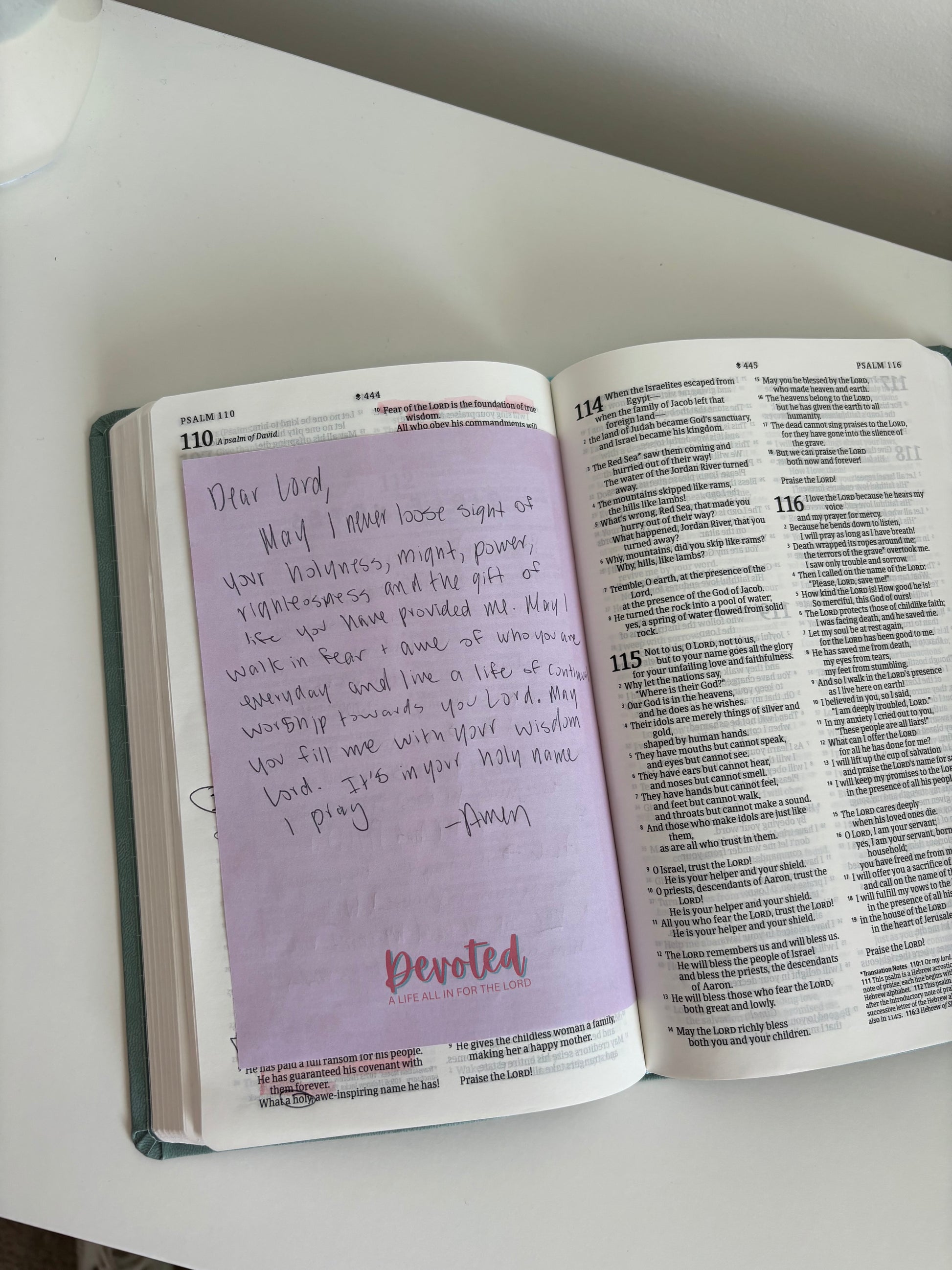 Open book with a purple page featuring handwritten text on a white surface.