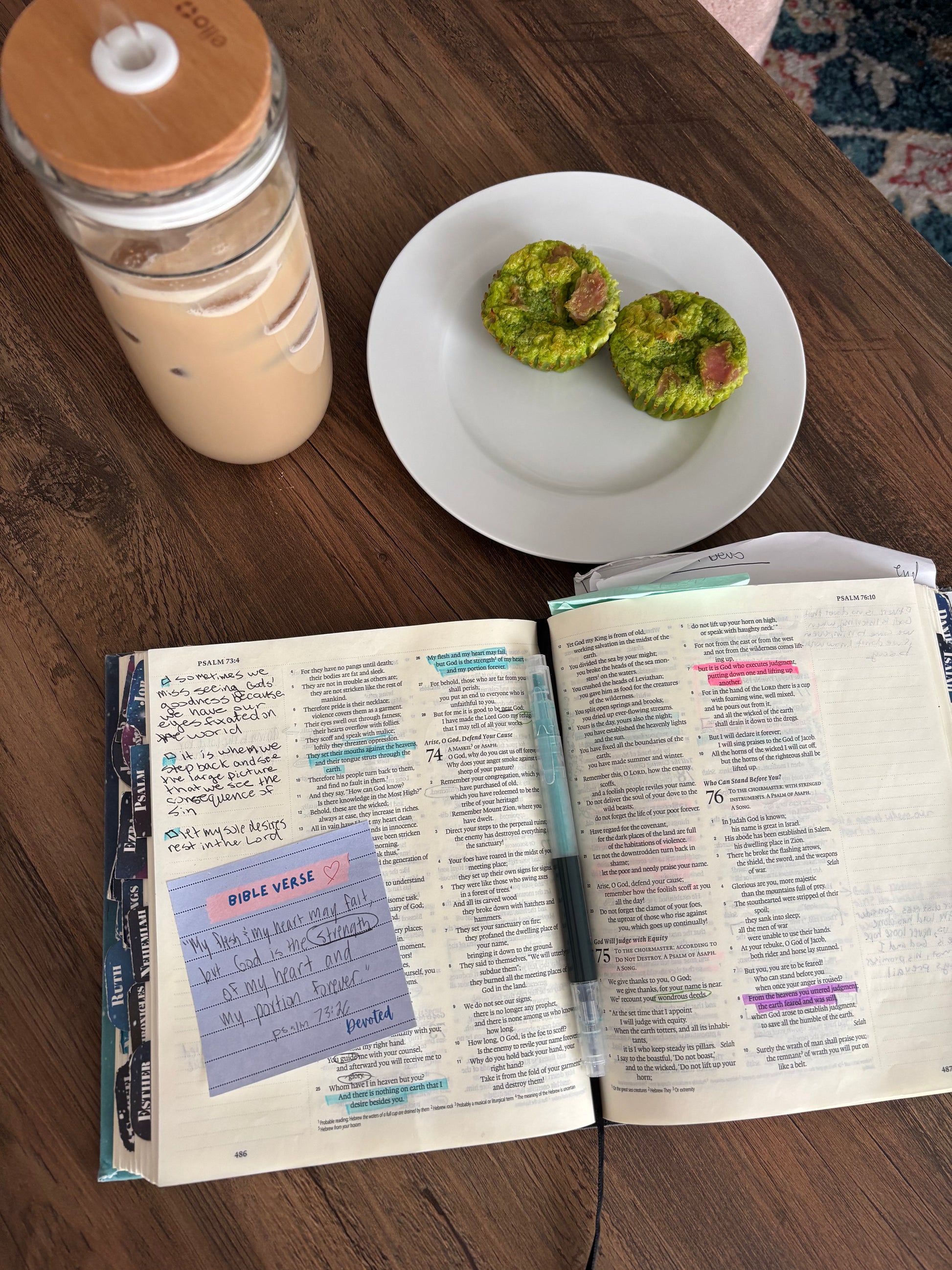 Open book with a sticky note, a cup of coffee, and two egg bites on a wooden table.