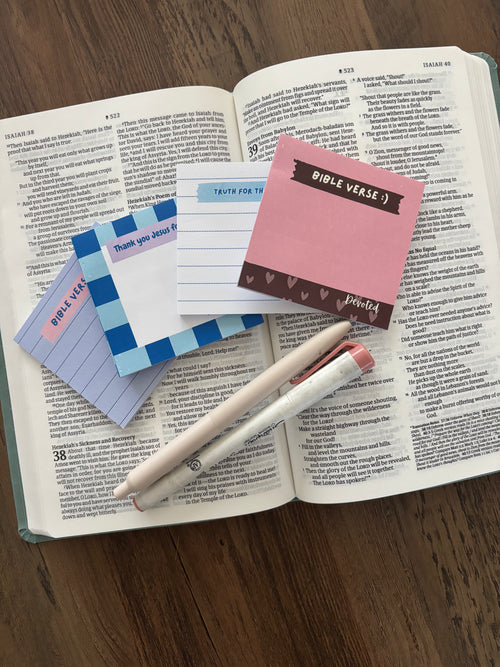 Open book with sticky notes and a pen on a wooden surface