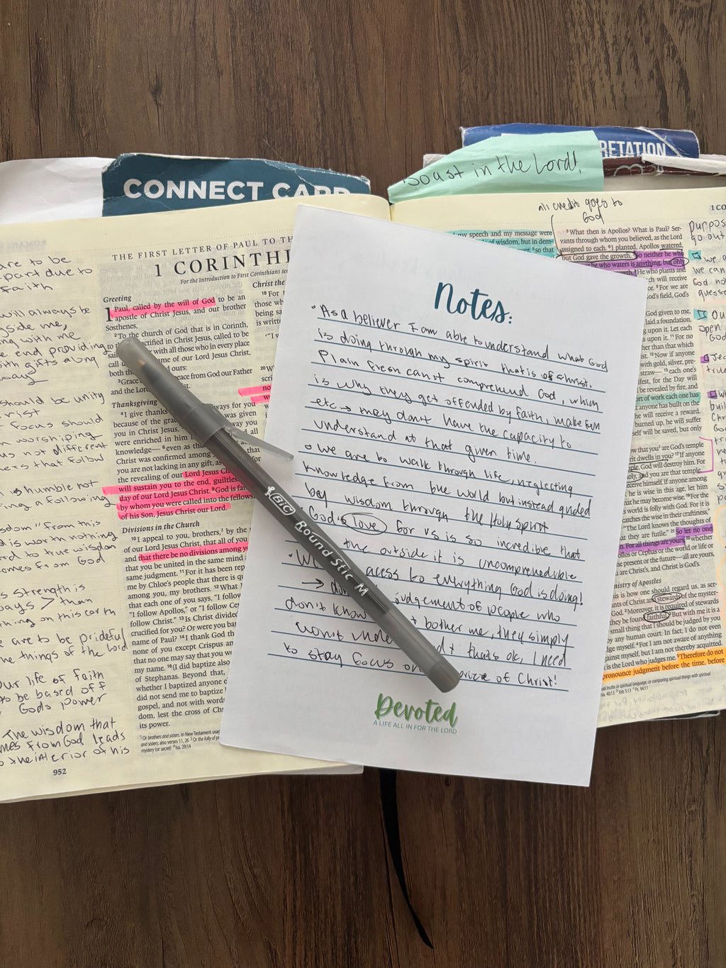 Open book with notes, a pen, and a card on a wooden surface