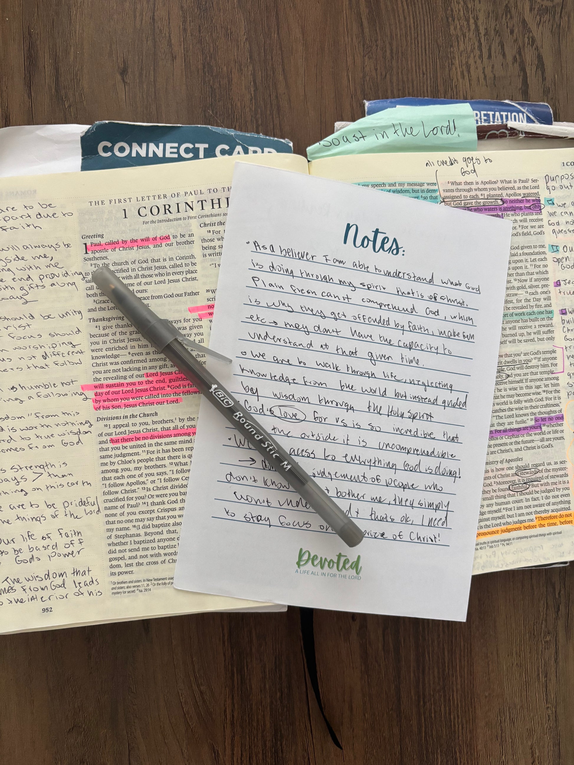 Open book with notes, a pen, and a card on a wooden surface