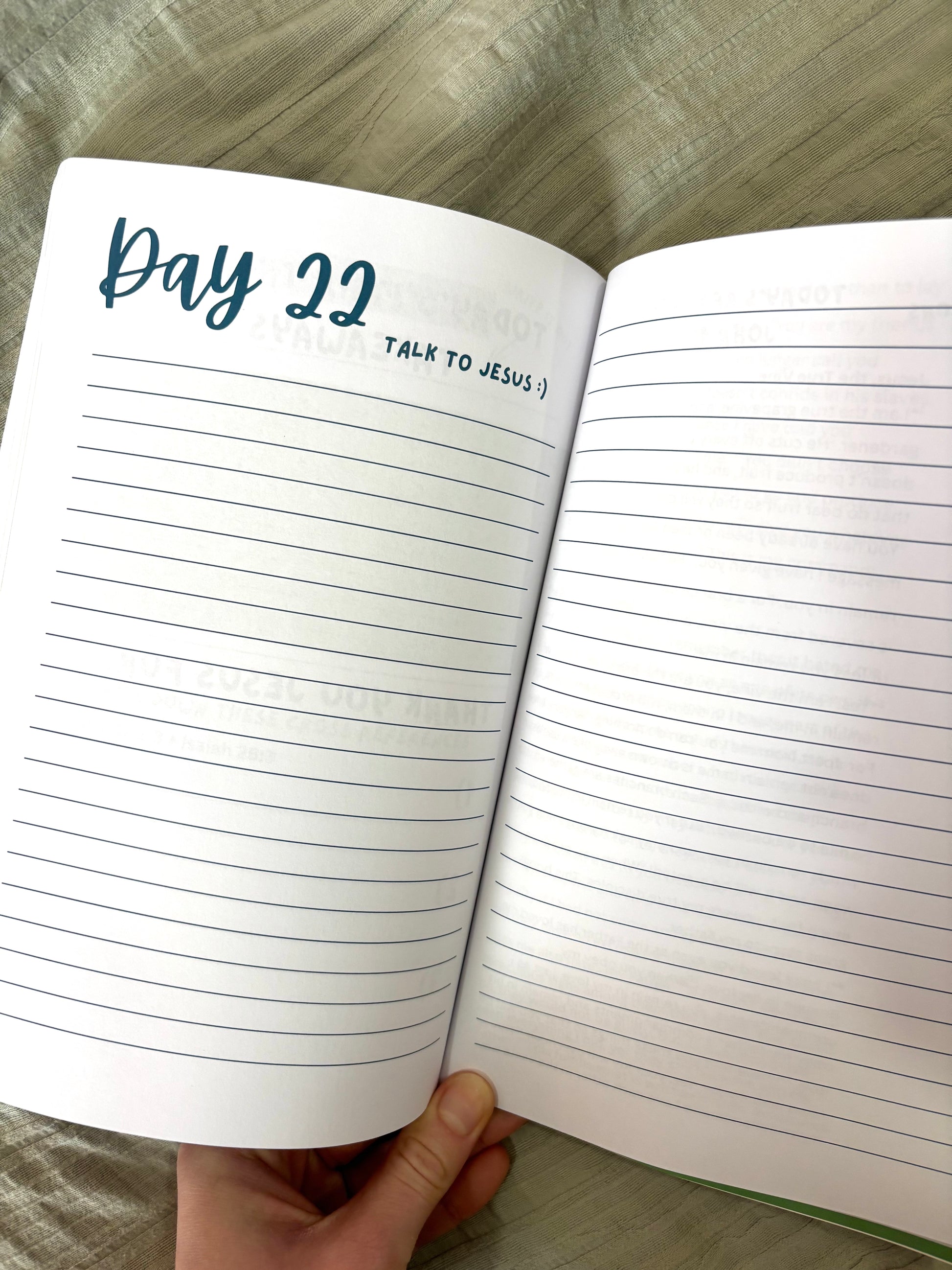 Open notebook with lined pages and 'Day 22 Talk to Jesus' text on a wooden surface.