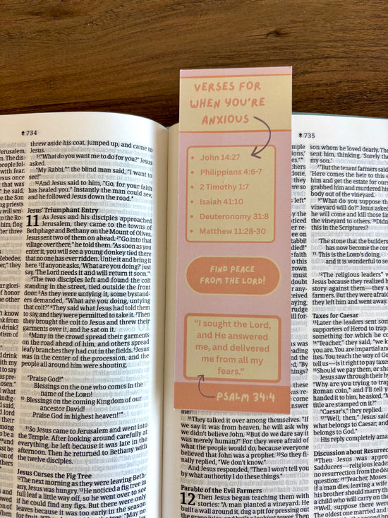 Open book with a pink bookmark titled 'Verses for When You're Anxious' on a wooden surface.