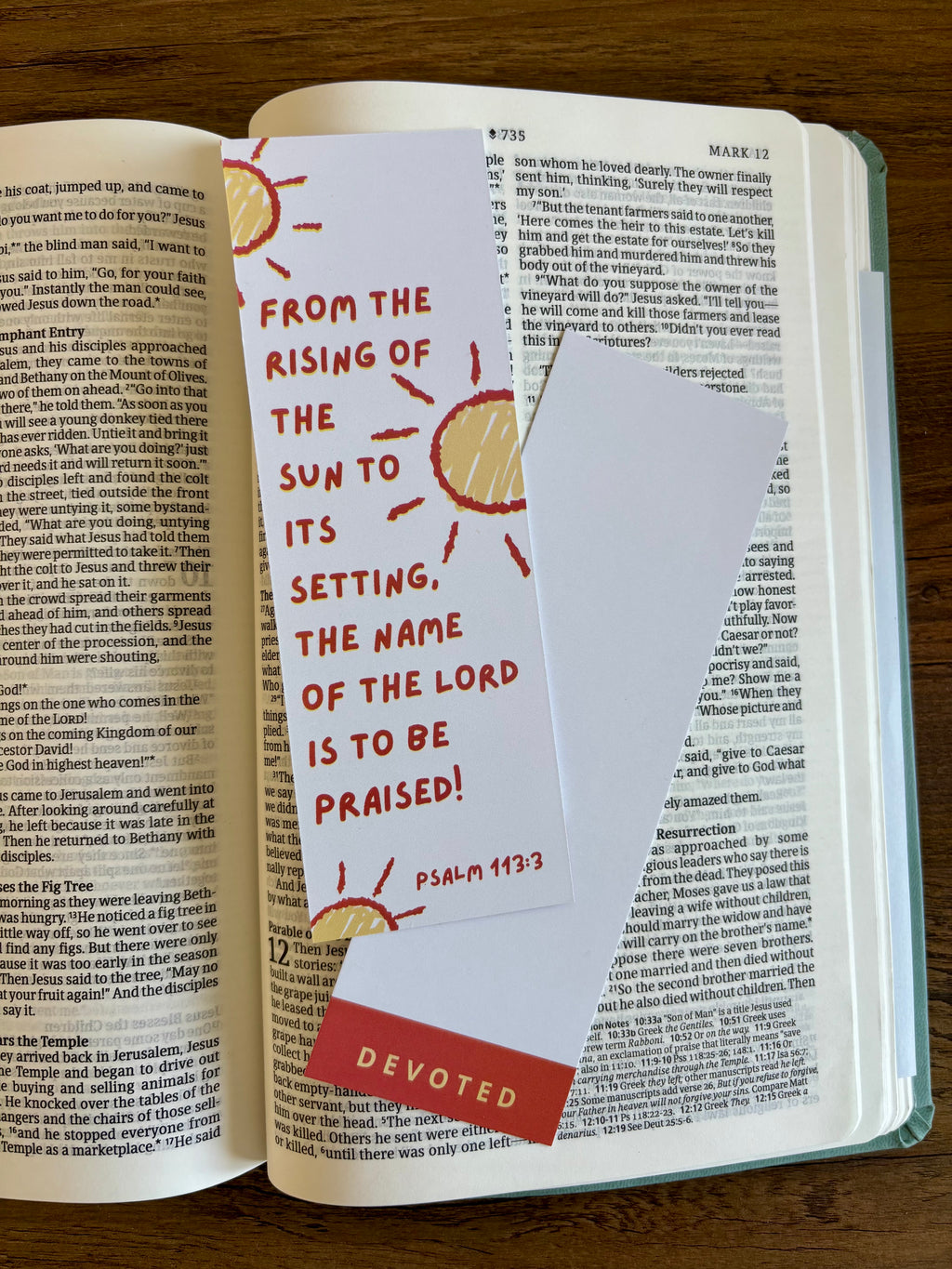 Open book with a bookmark featuring a sun illustration and text on a wooden surface