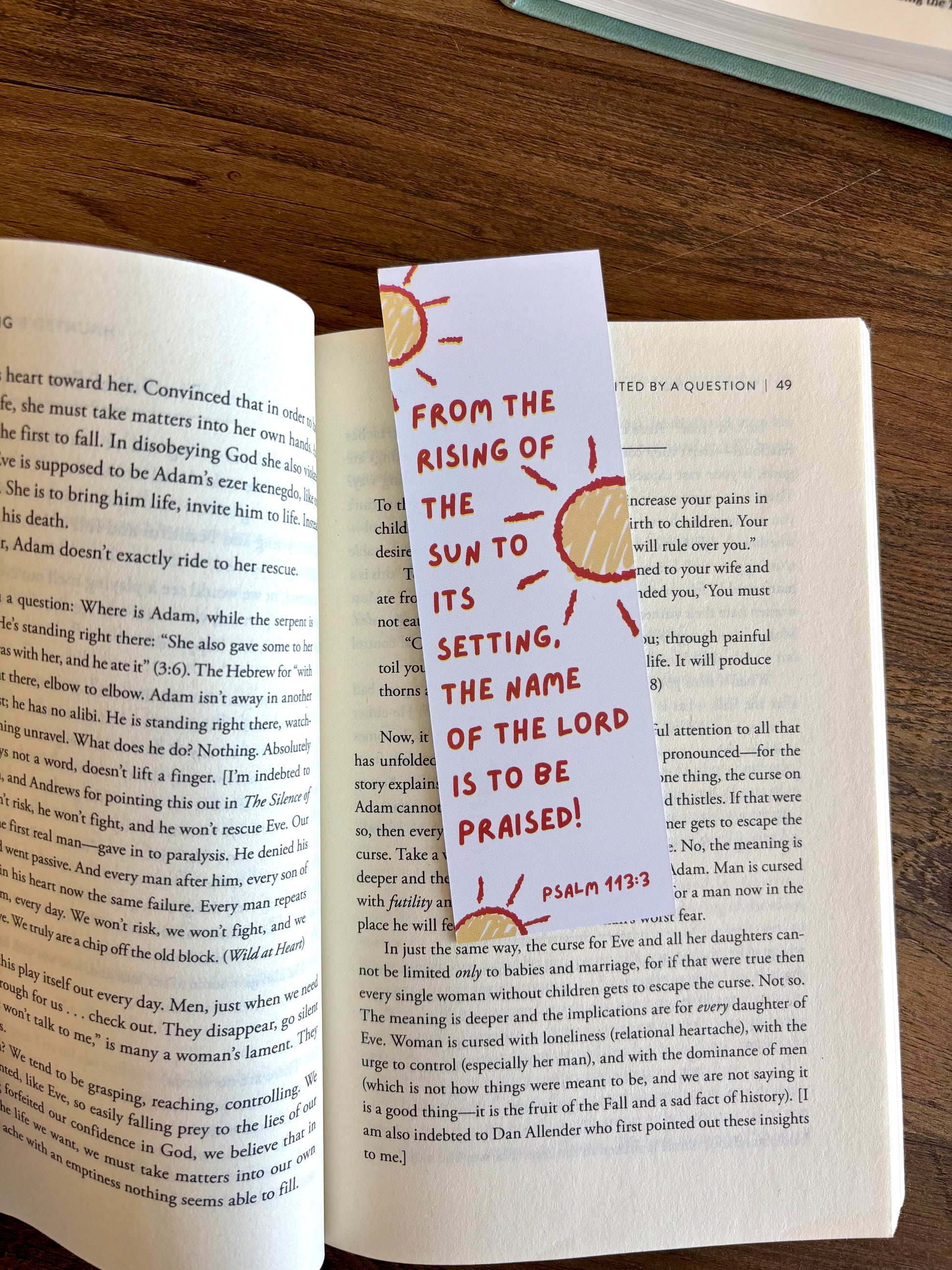 Book with a bookmark featuring Psalm 118:26 on a wooden surface