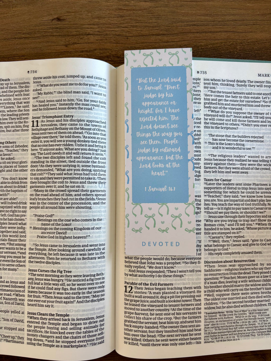 Open book with a bookmark featuring text and decorative elements on a wooden surface