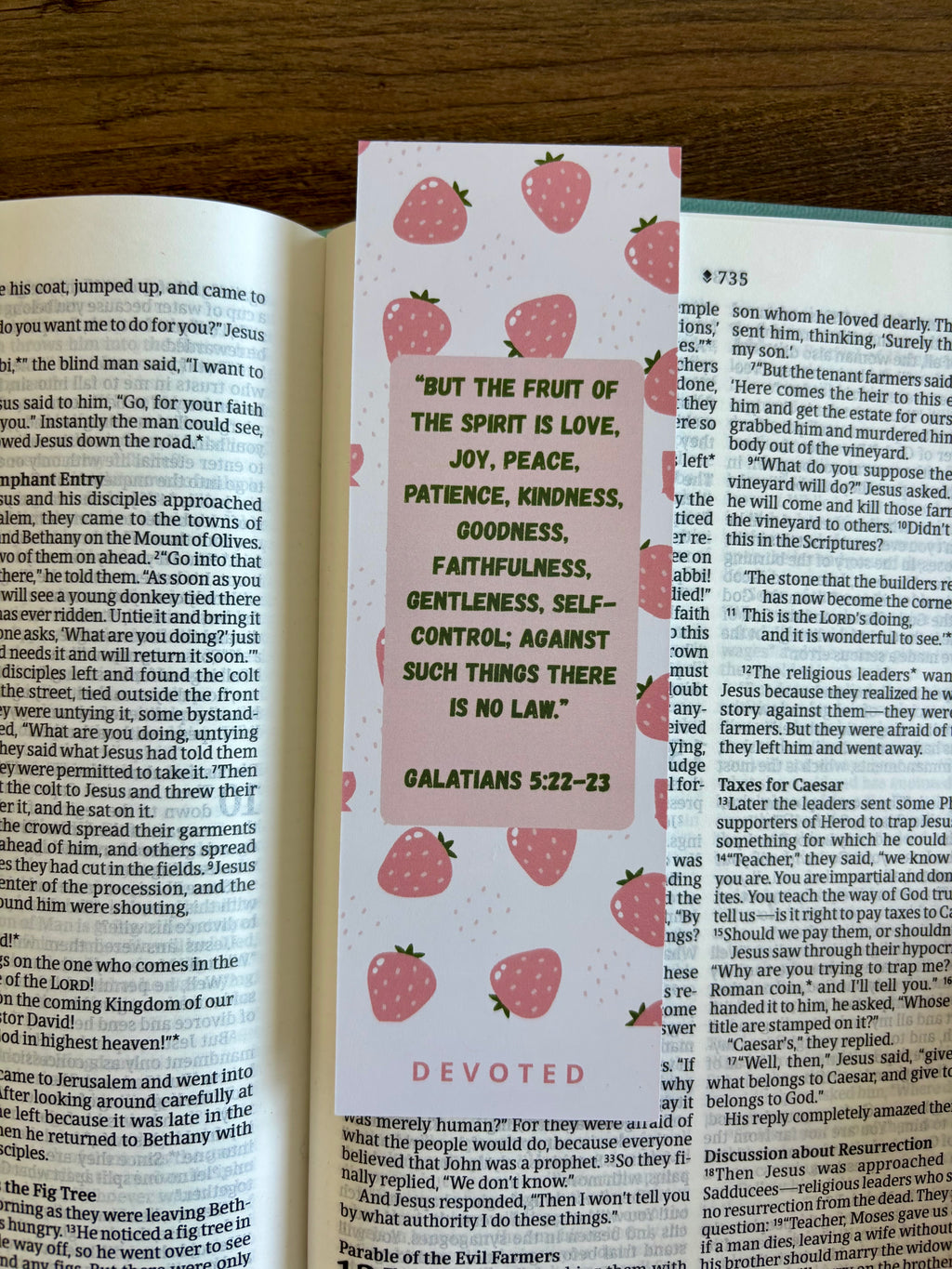 Bible with a strawberry-themed bookmark on a wooden surface