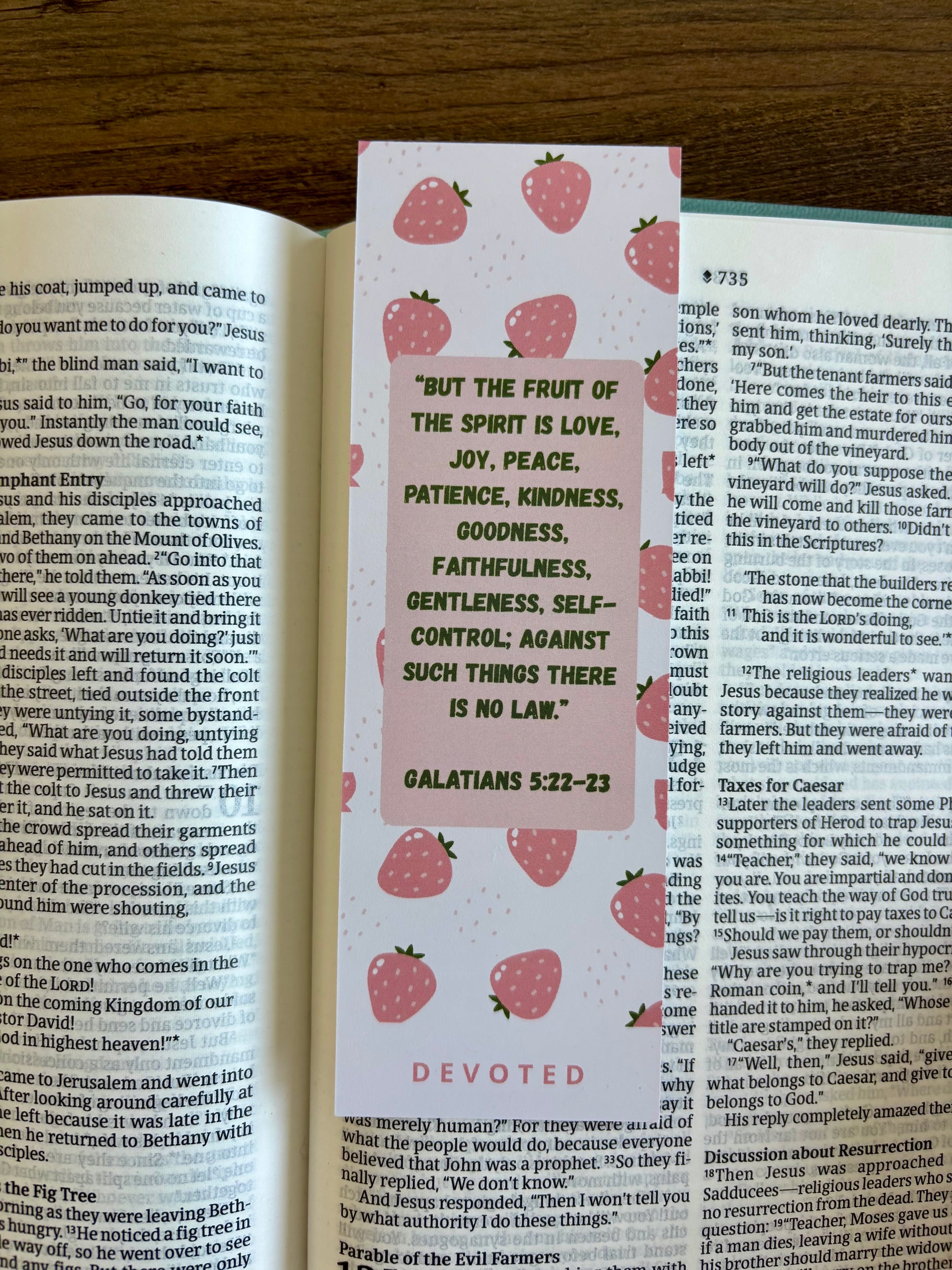 Bible with a strawberry-themed bookmark on a wooden surface