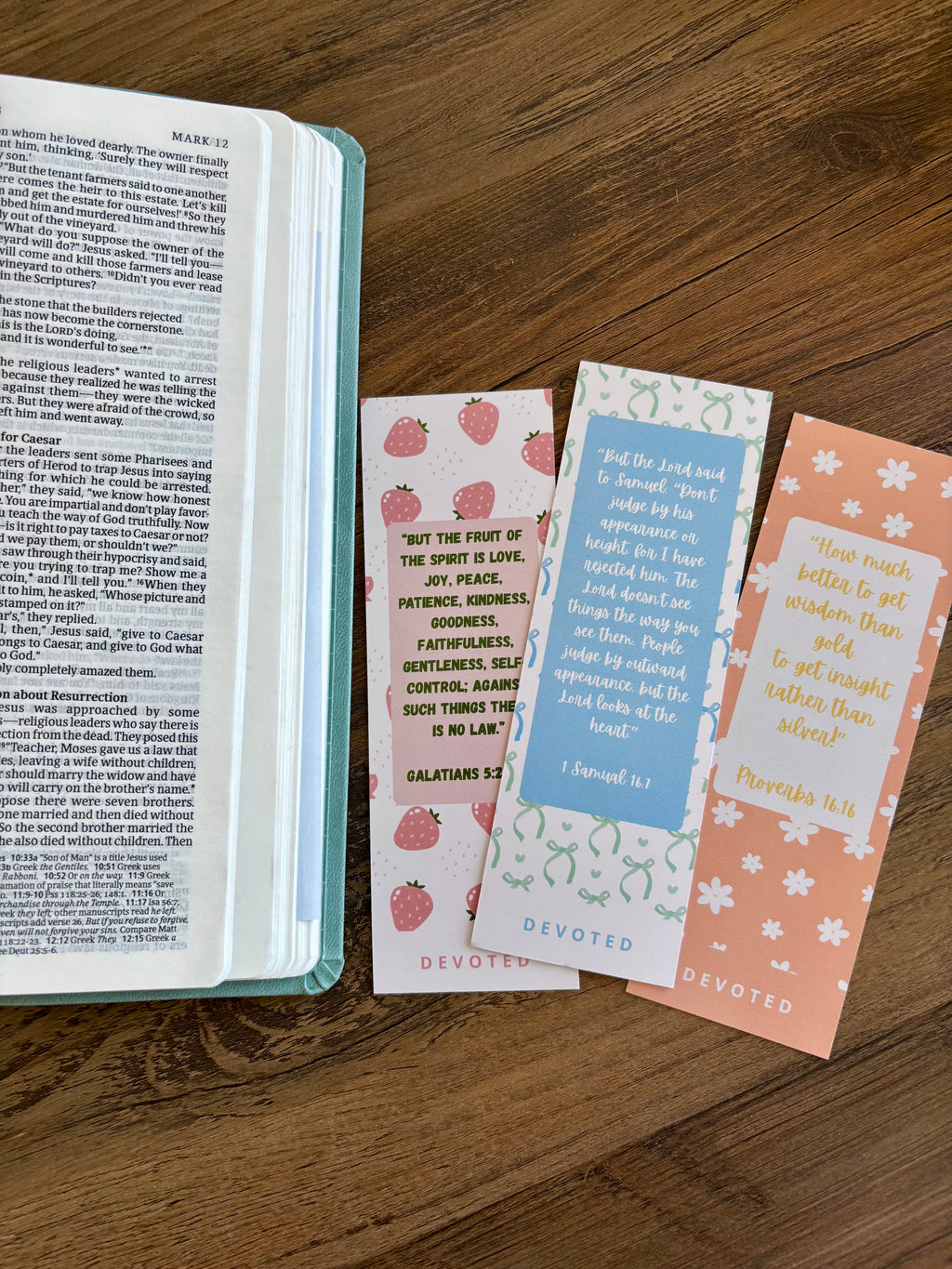 Open book with three decorative christian bookmarks on a wooden surface