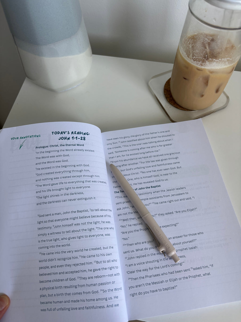An open Bible study on a desk with a coffee and pen