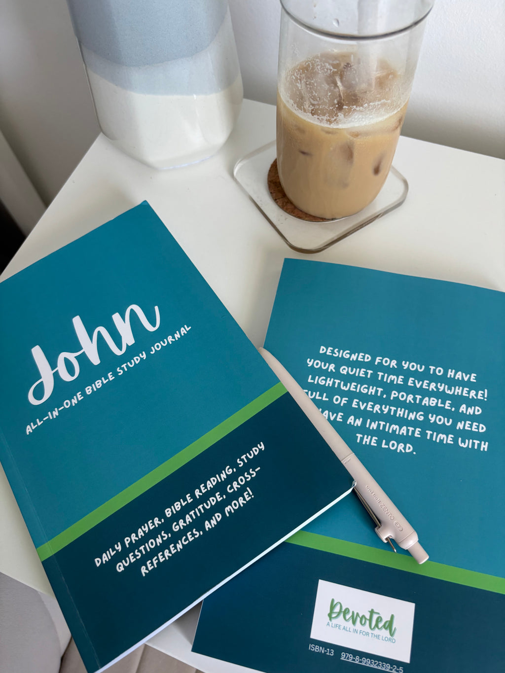 a stack of Bible study book through John on a desk with a pen and coffee
