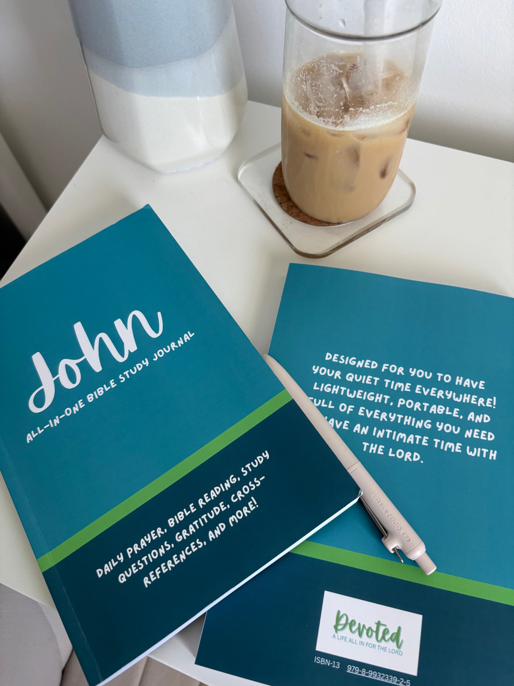 a stack of Bible study book through John on a desk with a pen and coffee
