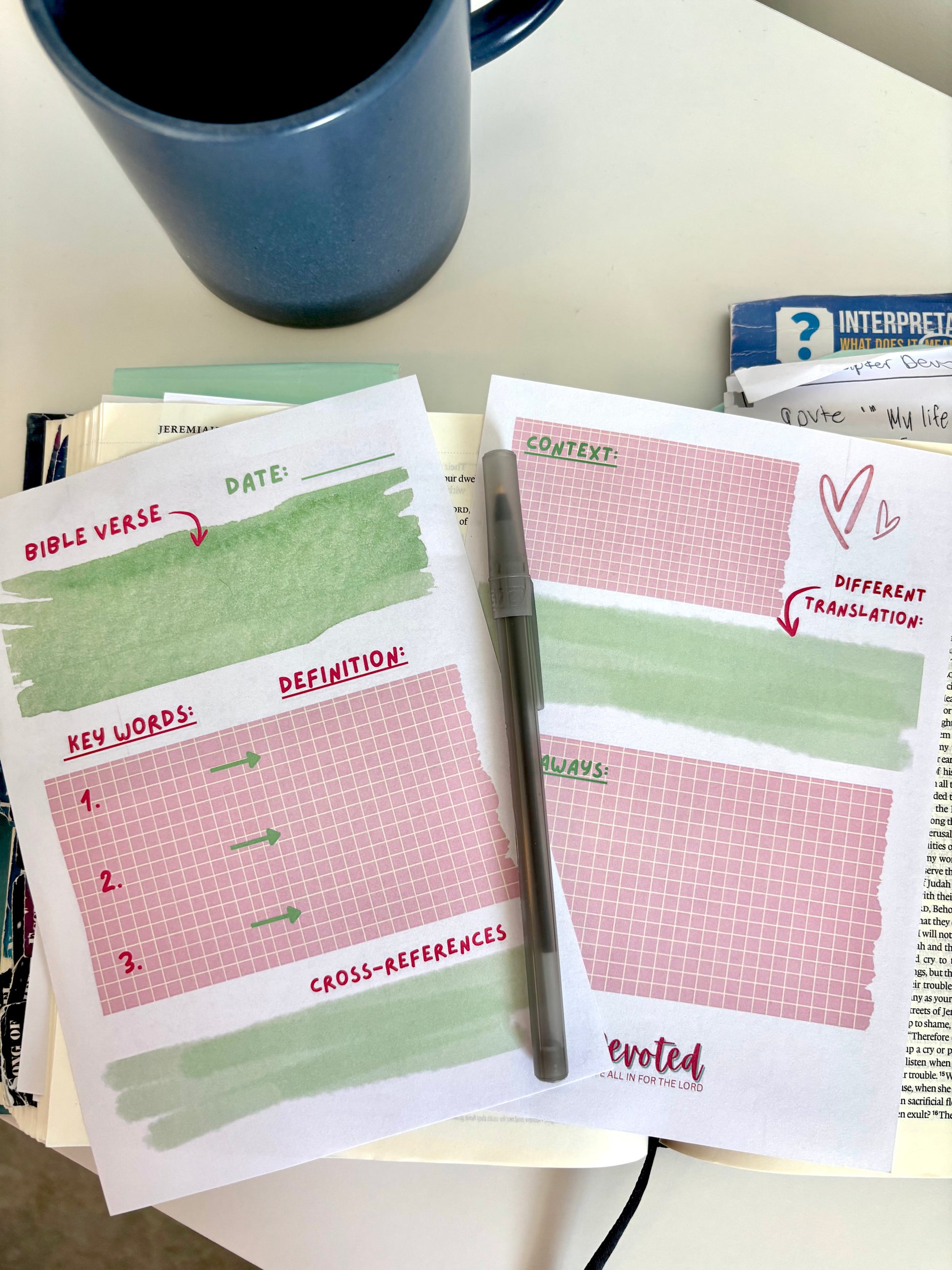 Two printed sheets with a pen on a table next to a blue mug.