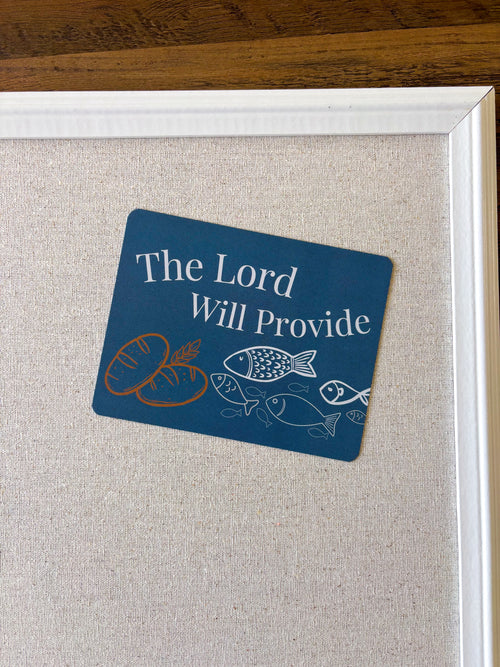 A christian postcard will drawn bread and fish on stating "the Lord will provide" displayed on a cork board.