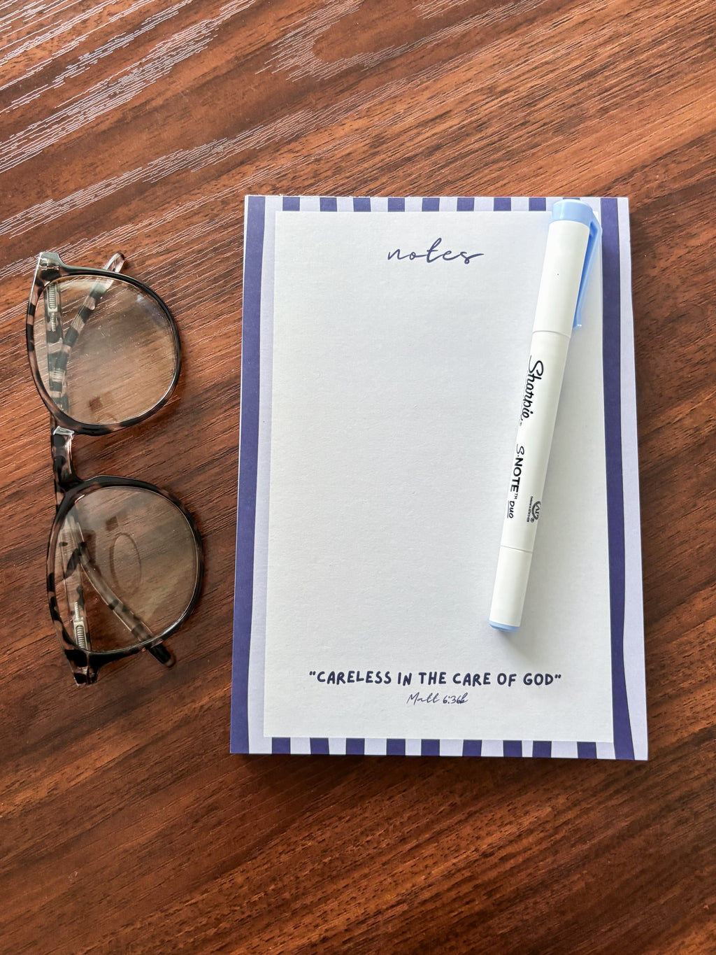 blank notepad on a brown coffee table with a marker on it and glasses