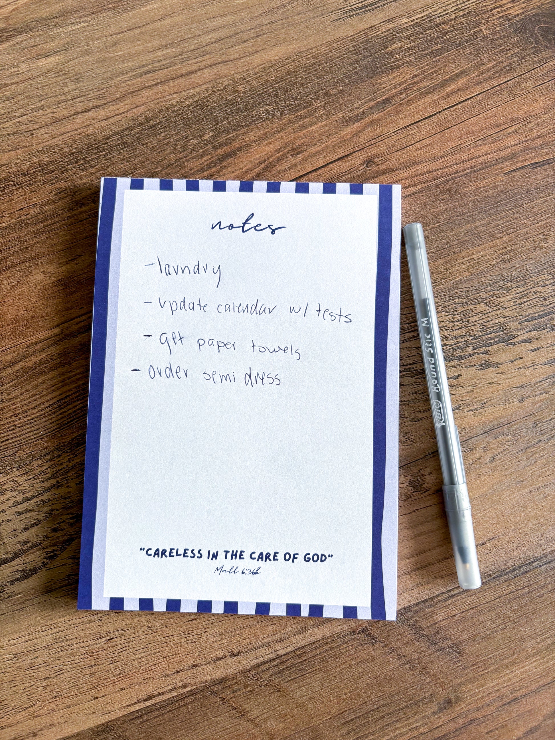 blue striped notepad with a bible verse on a brown coffee table with a pen