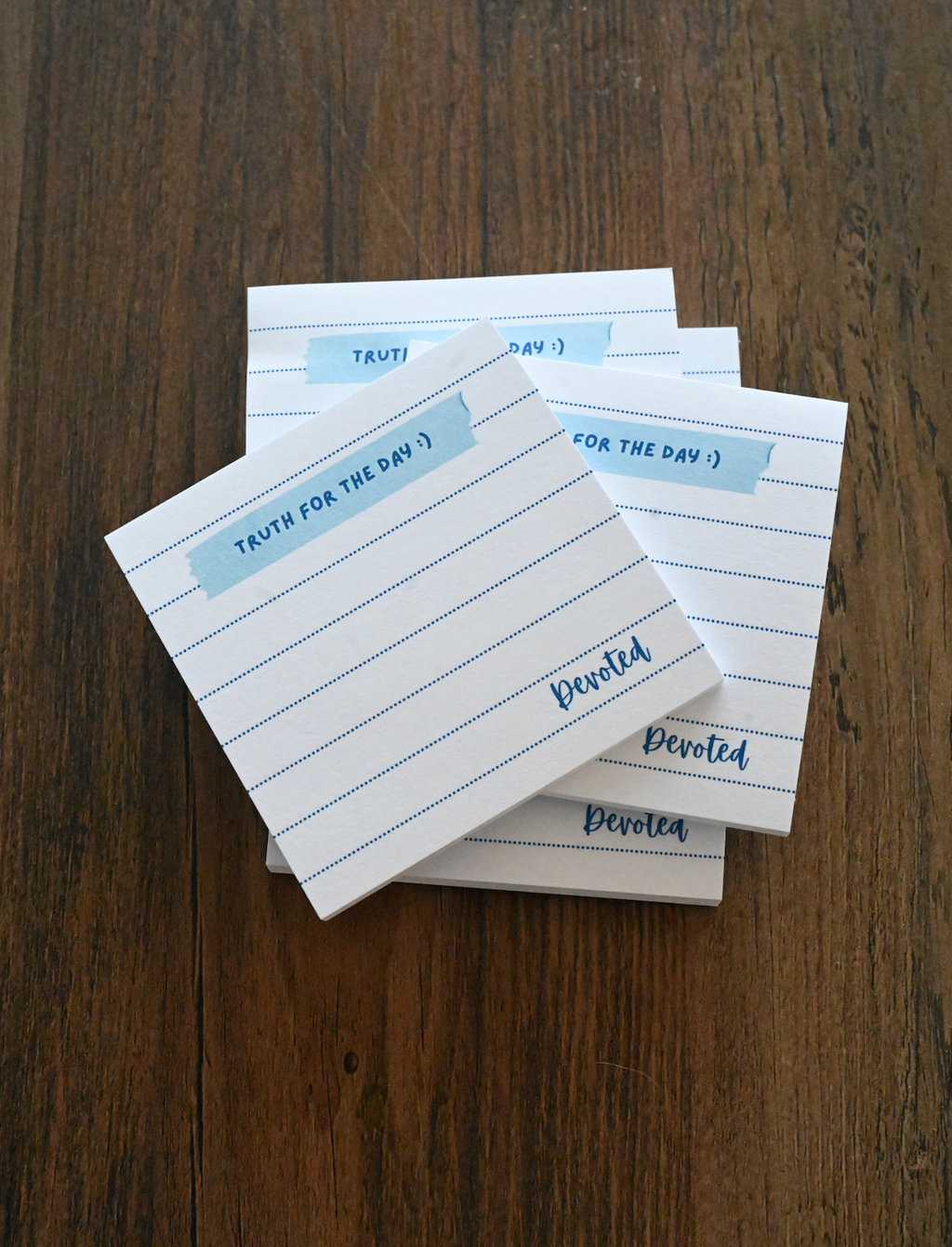 Stack of lined notepads with 'Devoled' branding on a wooden surface