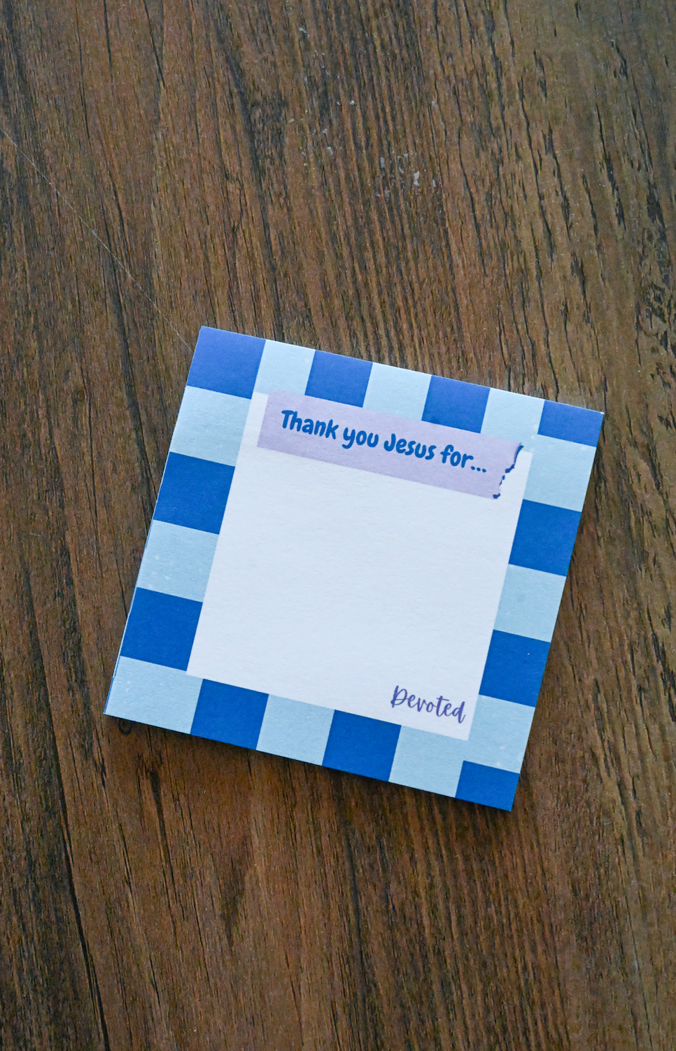 Checkered notepad with 'Thank you Jesus for' text on a wooden surface