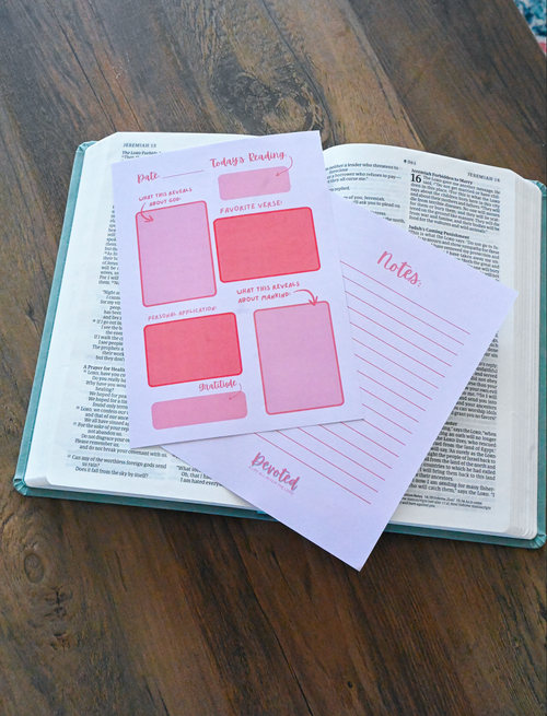 Open book with pink planner note pages on a wooden surface