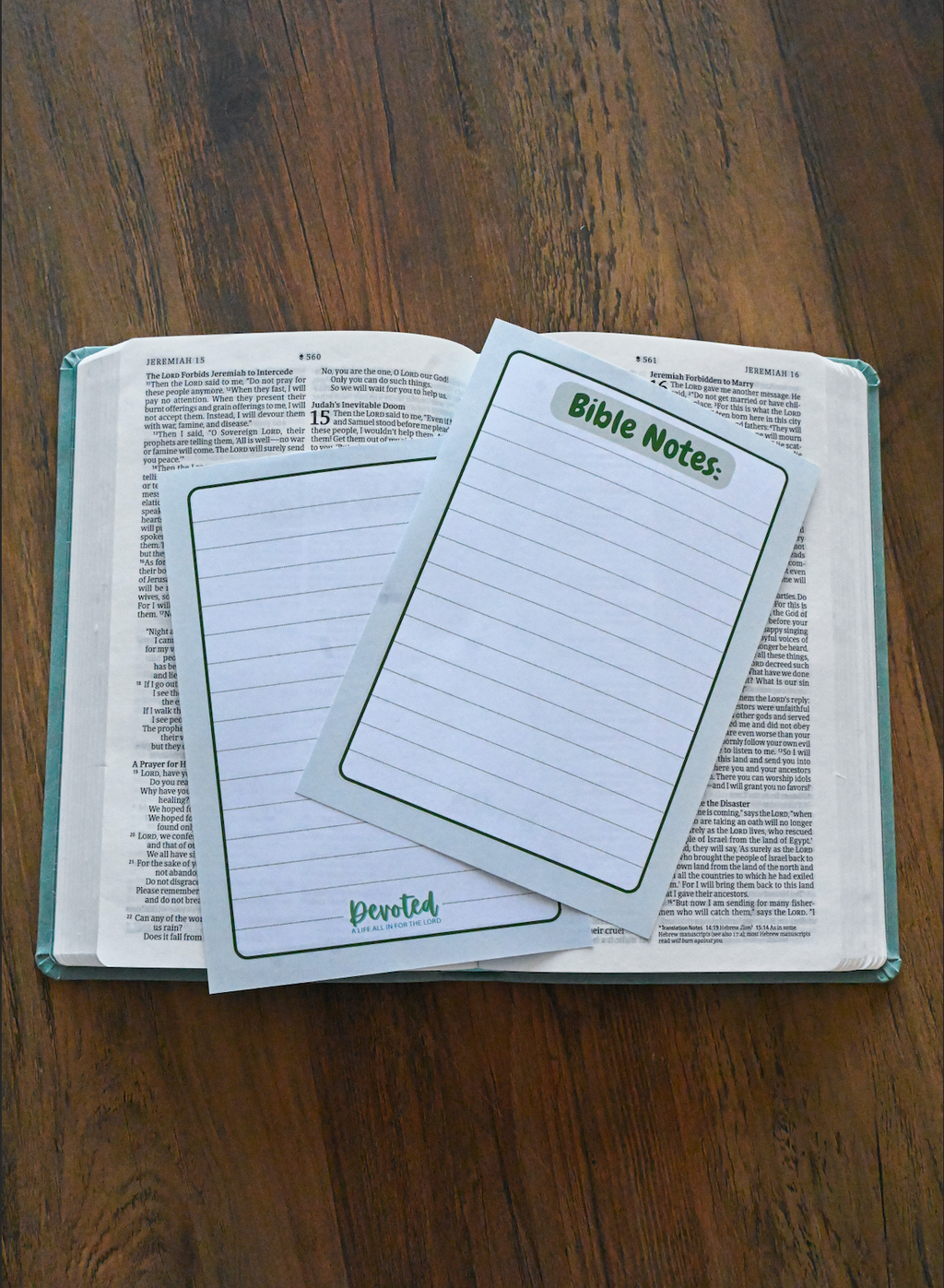 Two Bible note cards on an open Bible with a wooden surface background