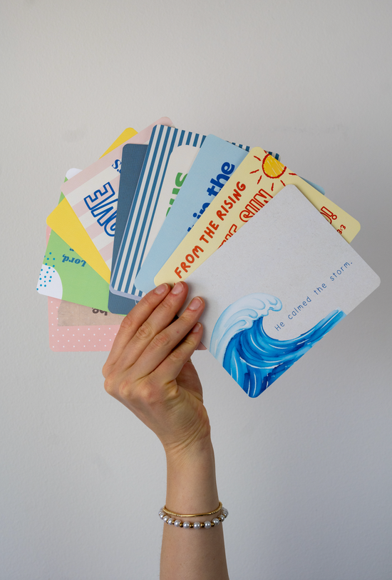 a hand holding a bunch of different christian postcards against a white wall